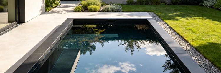 1783061699803349.png alt=Modern rectangular plunge pool with dark tile finish reflecting sky and trees in a minimalist garden.png